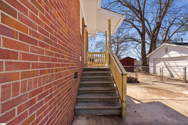 view of home's exterior featuring an outbuilding, a garage, brick siding, and fence