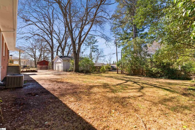 view of yard with an outdoor structure, central AC, and fence