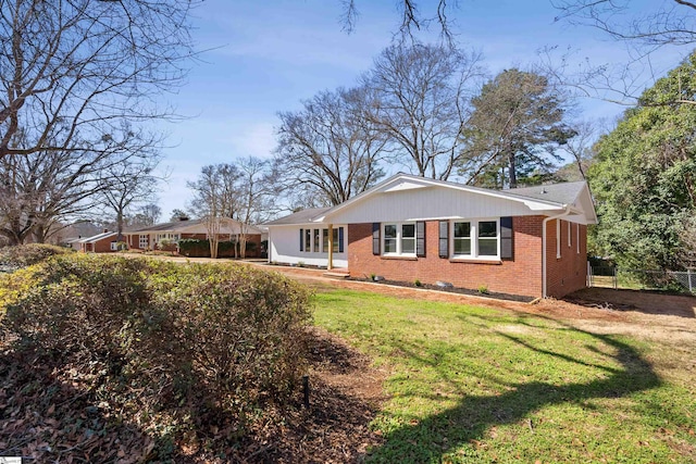 back of house with a yard, fence, and brick siding