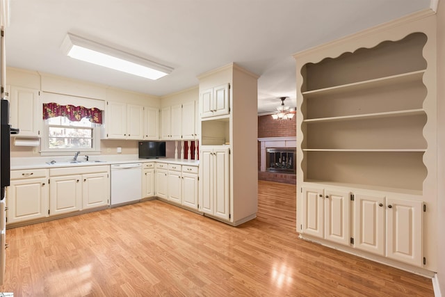 kitchen featuring light countertops, light wood-type flooring, white dishwasher, a ceiling fan, and a sink