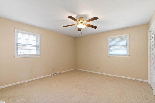 spare room with light colored carpet, a healthy amount of sunlight, and visible vents