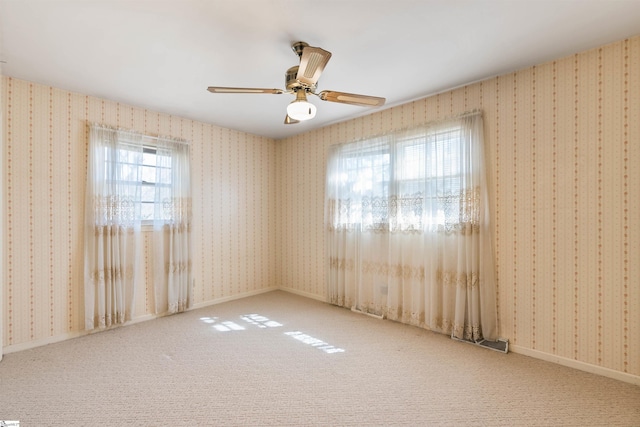 carpeted empty room with baseboards, wallpapered walls, and a ceiling fan