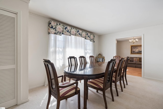 dining area with baseboards, light colored carpet, and an inviting chandelier