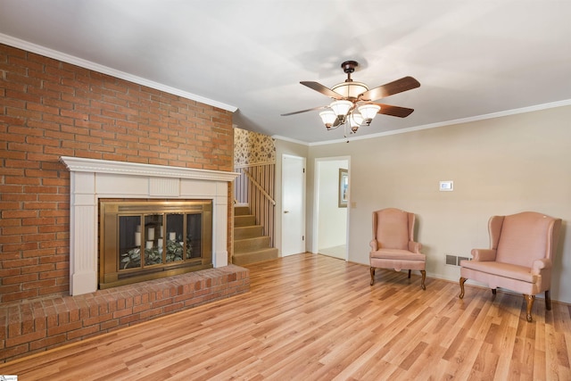 unfurnished room featuring visible vents, ornamental molding, wood finished floors, a fireplace, and ceiling fan