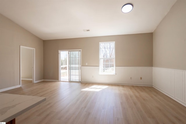 spare room with visible vents, wainscoting, and light wood-type flooring