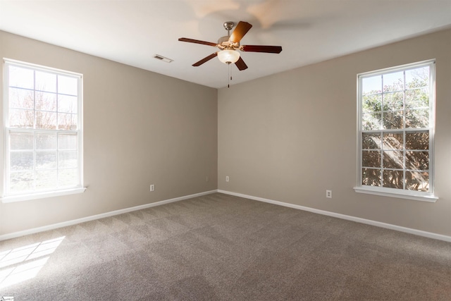 carpeted empty room featuring visible vents, plenty of natural light, a ceiling fan, and baseboards