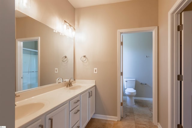 bathroom with double vanity, toilet, baseboards, and a sink