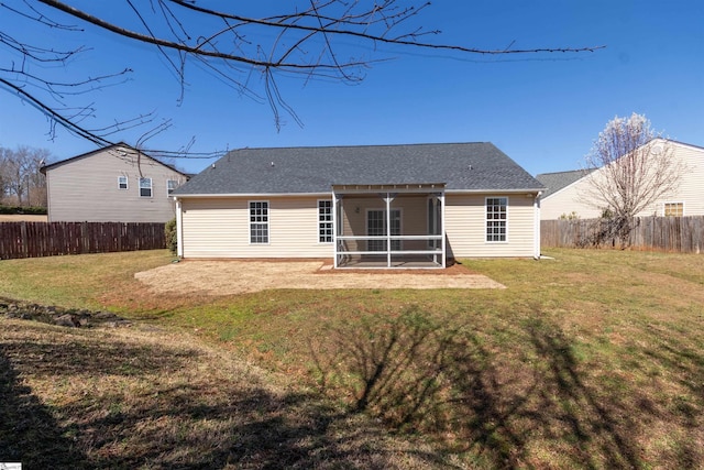 rear view of property with a lawn, a shingled roof, a fenced backyard, and a sunroom