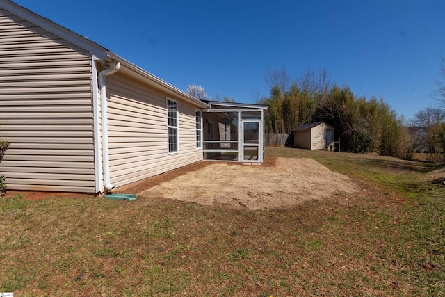 view of yard featuring a shed, an outdoor structure, and a sunroom