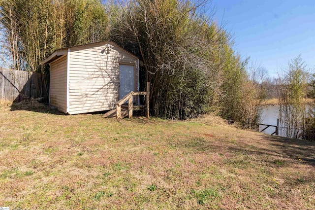 view of yard with a storage shed, fence, a water view, and an outdoor structure