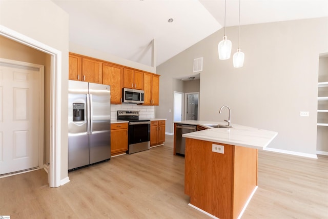 kitchen with visible vents, light wood finished floors, a sink, stainless steel appliances, and brown cabinets