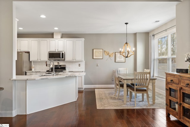 kitchen featuring backsplash, appliances with stainless steel finishes, white cabinets, and dark wood-style flooring