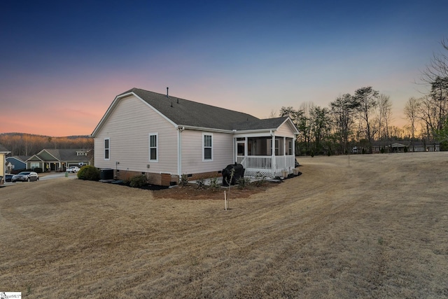 back of house at dusk featuring crawl space, central air condition unit, and a sunroom