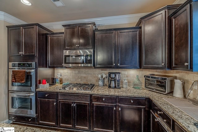 kitchen featuring light stone counters, backsplash, appliances with stainless steel finishes, and crown molding