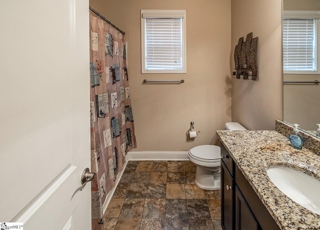 bathroom featuring a healthy amount of sunlight, toilet, vanity, and baseboards