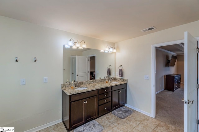 bathroom with double vanity, baseboards, visible vents, and a sink