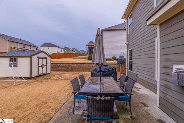 view of patio / terrace with an outbuilding, fence, outdoor dining area, a storage unit, and grilling area