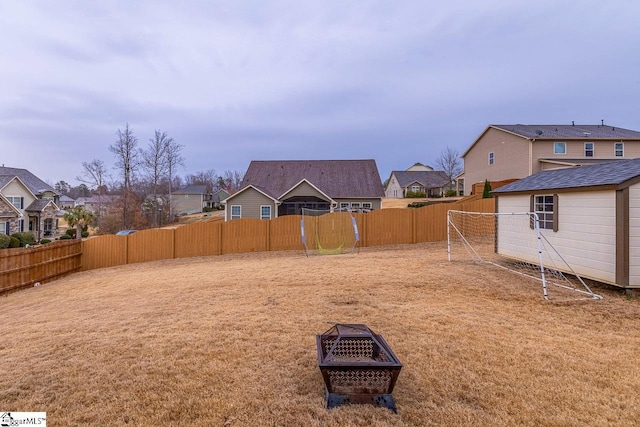 view of yard with a residential view, a fire pit, and a fenced backyard