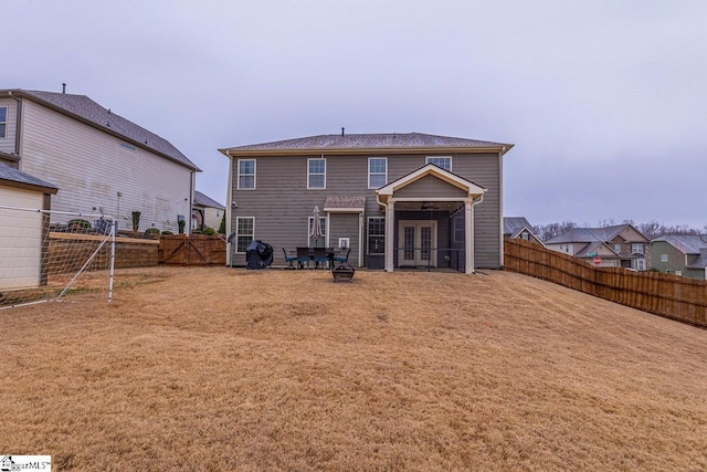 back of property with french doors, a yard, and a fenced backyard