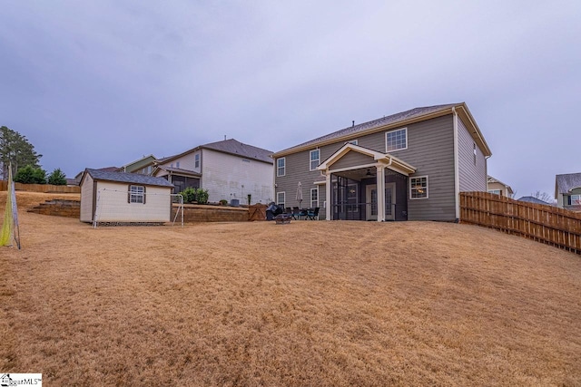 back of house with an outbuilding, a storage unit, a fenced backyard, and a sunroom