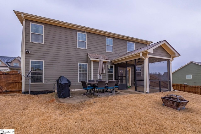 back of house featuring fence, a lawn, a sunroom, and an outdoor fire pit