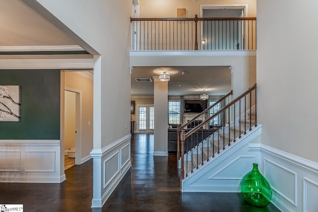 stairs featuring a decorative wall, wood finished floors, and ornamental molding