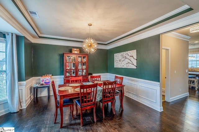 dining space with wood finished floors, visible vents, a wainscoted wall, crown molding, and a chandelier