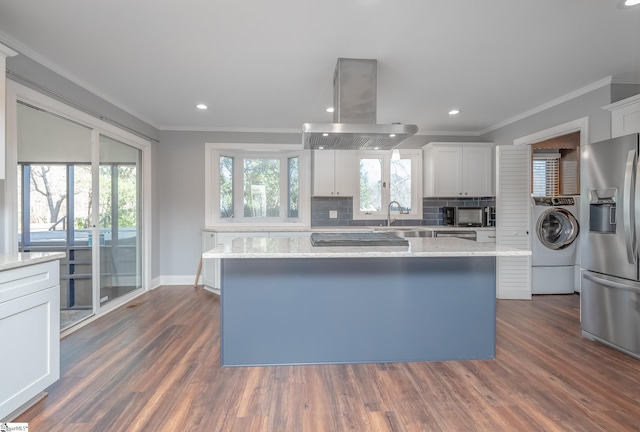 kitchen with black appliances, island range hood, crown molding, and washer / dryer