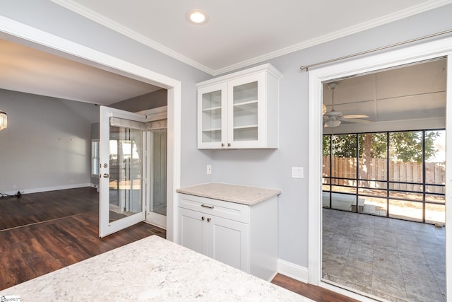 interior space with baseboards, dark wood-type flooring, ceiling fan, and crown molding