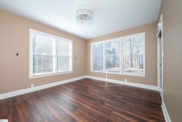 unfurnished room with dark wood finished floors, baseboards, and a wealth of natural light