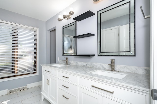 bathroom with a sink, visible vents, baseboards, and double vanity