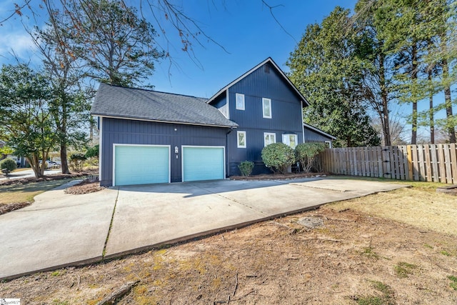 exterior space with an attached garage, a shingled roof, driveway, and fence