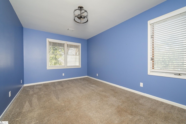 spare room with carpet flooring, visible vents, and baseboards