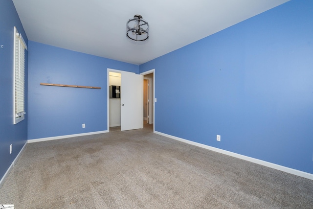 spare room with baseboards and carpet floors