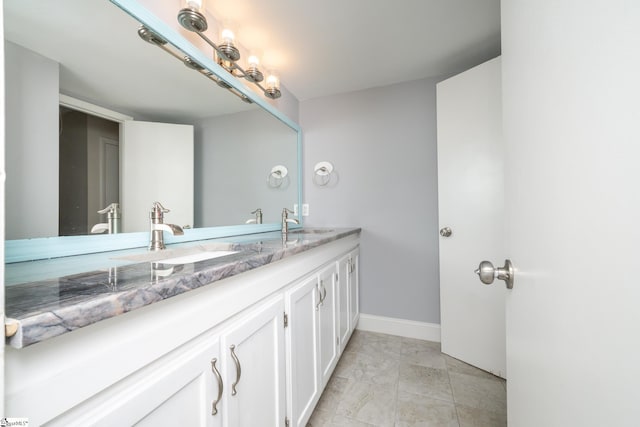 bathroom featuring tile patterned flooring, double vanity, baseboards, and a sink