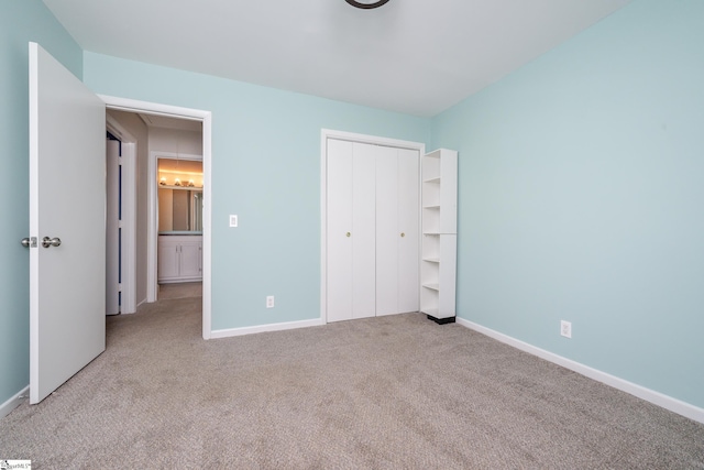 unfurnished bedroom featuring a closet, carpet flooring, attic access, and baseboards