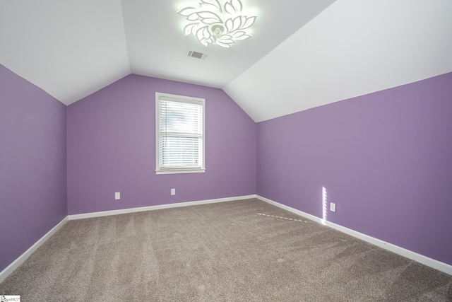 additional living space with visible vents, lofted ceiling, baseboards, and carpet floors