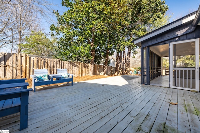 wooden deck with a fenced backyard and a sunroom