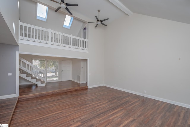 unfurnished living room with beam ceiling, a skylight, a ceiling fan, and a wealth of natural light