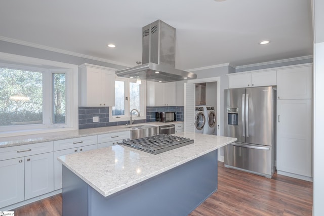 kitchen with decorative backsplash, appliances with stainless steel finishes, crown molding, washing machine and dryer, and island range hood