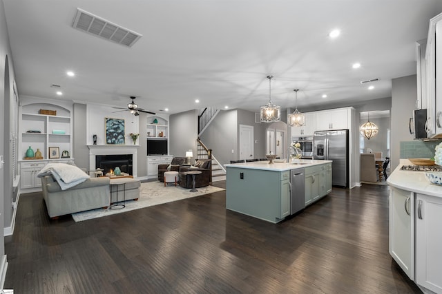 kitchen featuring stainless steel appliances, visible vents, a warm lit fireplace, and light countertops