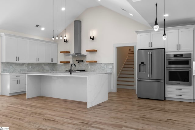 kitchen featuring light wood finished floors, wall chimney range hood, light countertops, stainless steel appliances, and open shelves