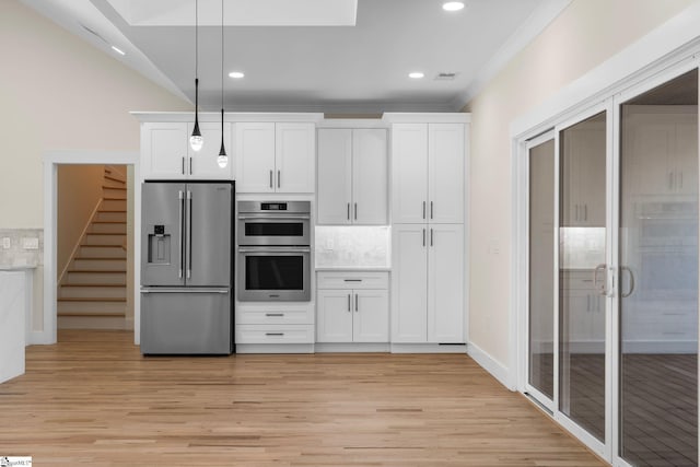 kitchen with tasteful backsplash, white cabinetry, stainless steel appliances, and light wood-style floors