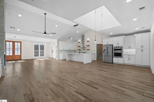 unfurnished living room with visible vents, ceiling fan, french doors, and light wood finished floors