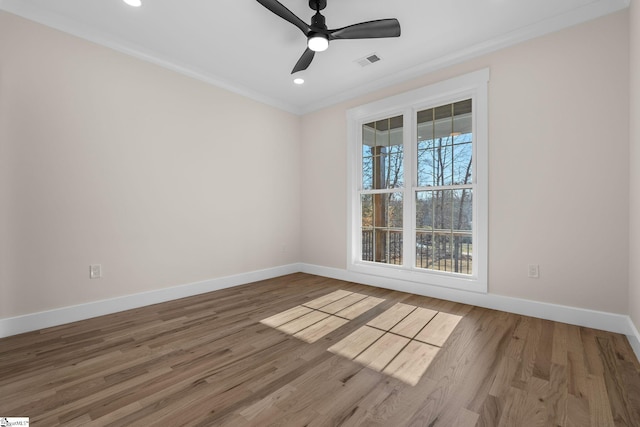 empty room featuring visible vents, ornamental molding, baseboards, and wood finished floors