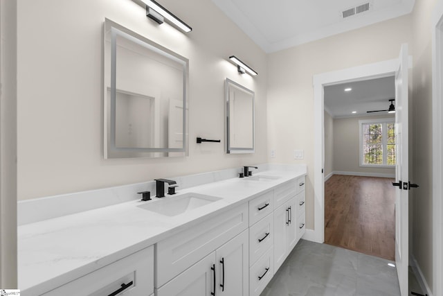 bathroom featuring double vanity, crown molding, visible vents, and a sink