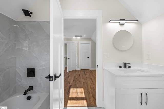 bathroom with vanity, wood finished floors, visible vents, bathtub / shower combination, and vaulted ceiling