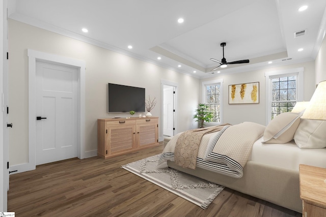 bedroom with a tray ceiling, multiple windows, wood finished floors, and crown molding