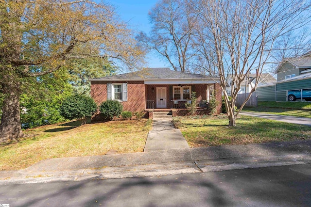 bungalow-style house with brick siding, covered porch, ceiling fan, and a front lawn