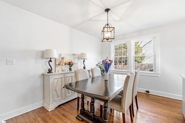 dining room with baseboards, an inviting chandelier, and light wood-style flooring